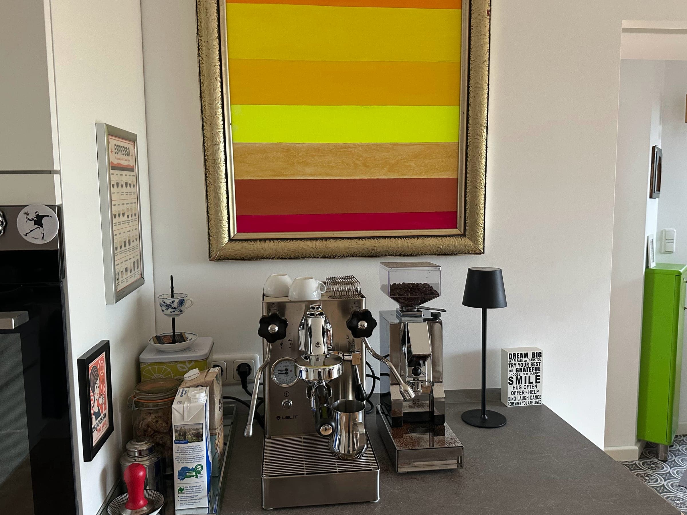 Ein Gemälde von Mitsch Schulz in goldenem Rahmen über einer Espressomaschine